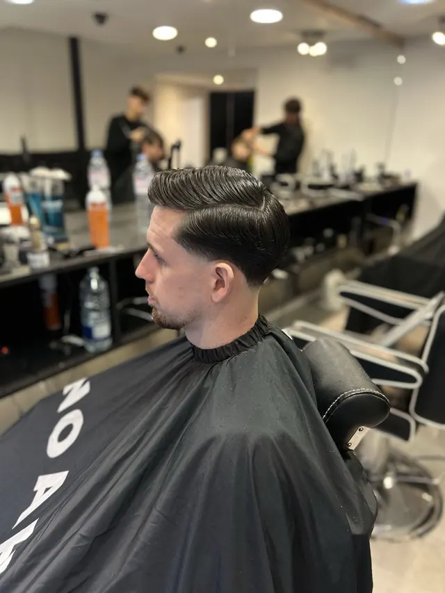 A client in the chair at Noahs Barbers, in the shop's own branded cape